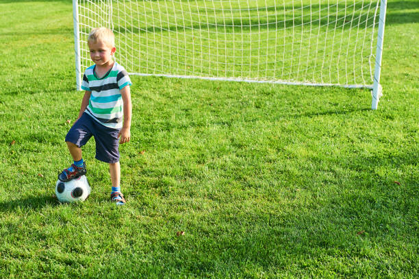 netter kleiner blonder junge, der als torwart spielt - playing field goalie soccer player little boys stock-fotos und bilder