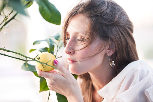 Young woman enjoying scented lemon on lemon tree