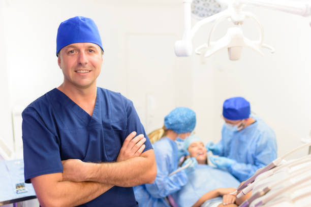 Dentist Portrait at Clinic Portrait of happy male dentist and his team at clinic easy test stock pictures, royalty-free photos & images