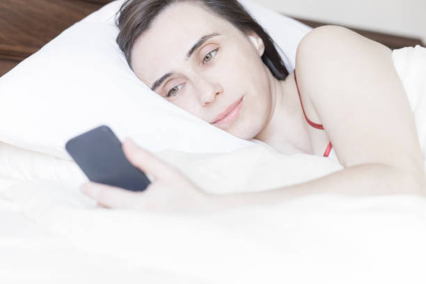 istock Woman lying on bed checking mobile phone in the morning 638689054