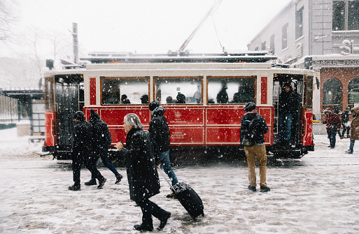 Istanbul, Turkey - January 8, 2017: Nostalgic Trams passing through Crowded Istiklal street in a snowy winter day in Taksim, Beyoğlu, Istanbul, Turkey.