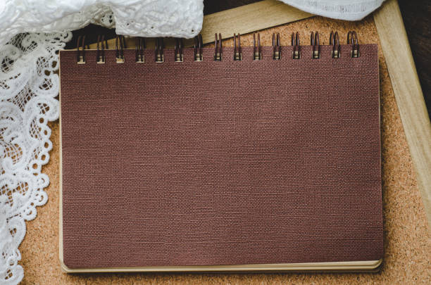 istock Brown notebook with lace on corkboard and wooden background 638690576