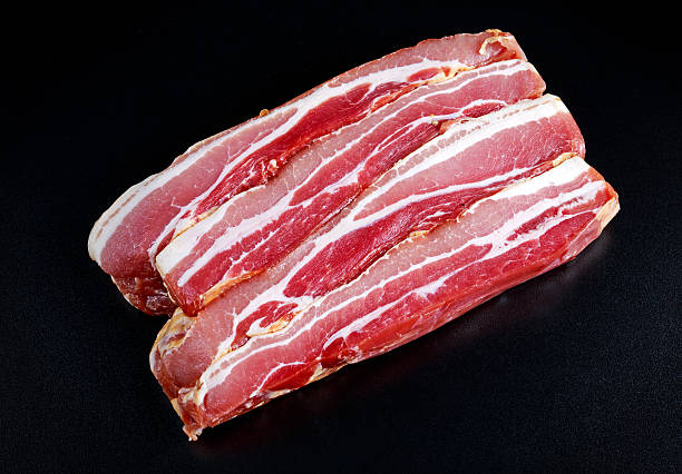 istock Raw smoked streaky sliced bacon on black board background 638692288