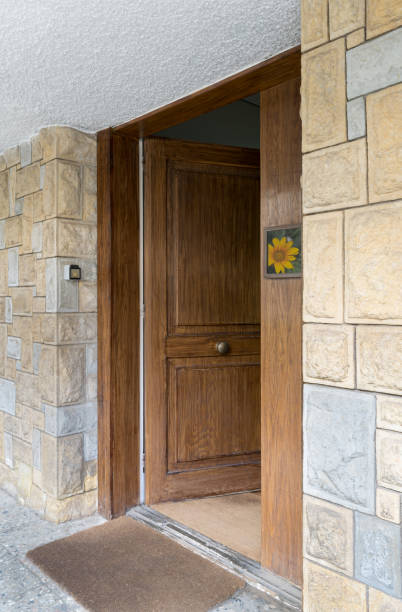 istock Half opened front wooden door at a stone bricks wall 638692560
