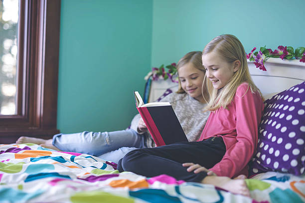 istock Two sisters reading together in their bedroom 638694332