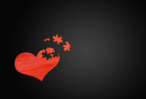 Red wooden puzzle heart on black wooden background