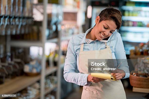 Woman At A Grocery Store Talking On The Phone Stock Photo - Download Image Now - Delivering, Owner, Store