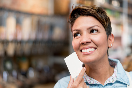 Portrait of a thoughtful woman holding a business card - small business concepts