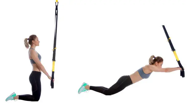 Athletic woman performing a functional exercise with suspension cable.