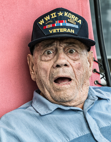 A proud, authentic, real person, elderly 93 year old senior adult man World War II and Korean Conflict United States Army military service veteran is looking at the camera with a humorous, exaggerated, shocked, surprised look of disbelief on his face. His brown eyes are wide open staring and his mouth is also wide open. An authentic look, but artificial this time. He was just playing around having fun mugging for the camera. :)