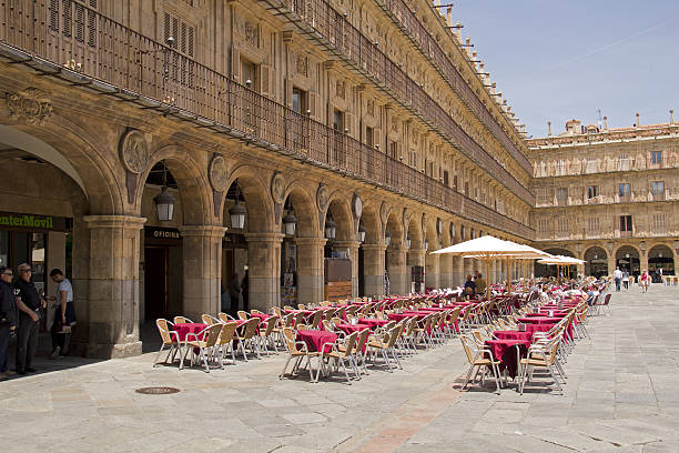 Salamanca, Spain - June 2, 2016: Tables and chairs of a restaurant and people walking on the historical Plaza Mayor,or main square, in the old center of Salamanca, Spain on June 2, 2016