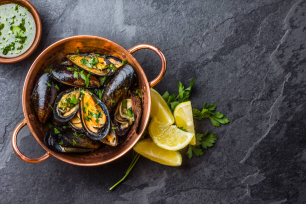 Mussels in copper bowl, lemon, herbs sauce and white wine. stock photo
