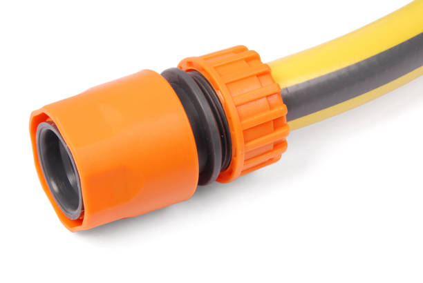 Yellow garden water hose and orange nozzle, isolated on white background with soft shadow