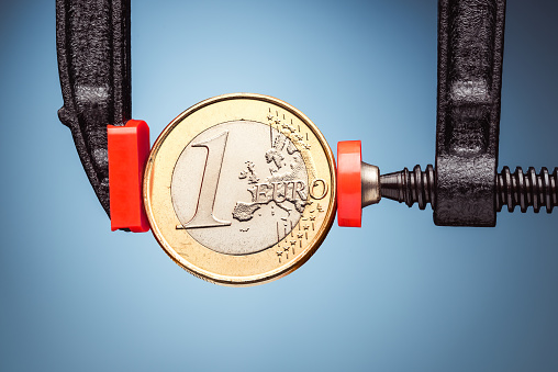 One Euro coin under pressure. Crisis concept.