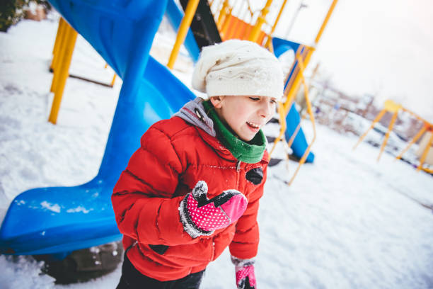 маленькая девочка играет в снегу - playground snow winter little girls стоковые фото и изображения