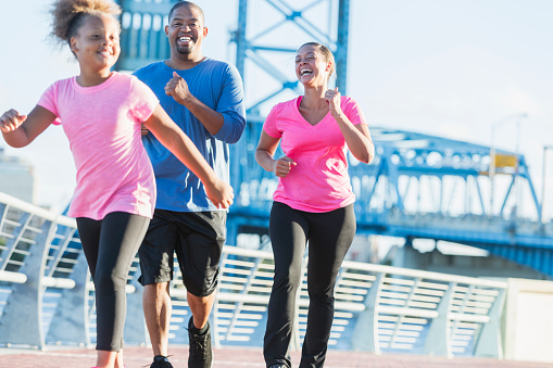Black family staying fit, power walking on waterfront