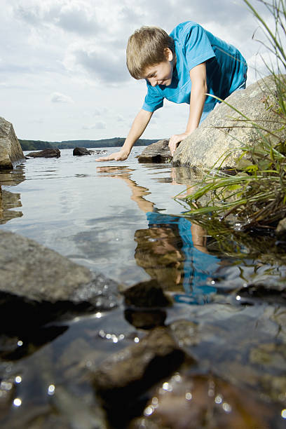 istock Boy touching surface of water at lake side in nature 638712638