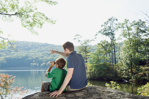 Father and son with binoculars looking at view in nature