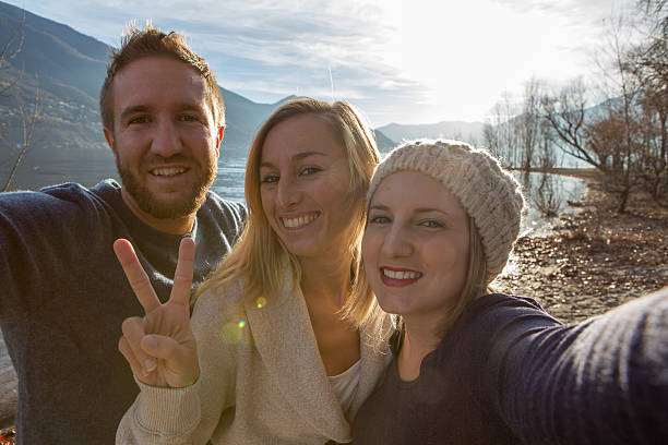 istock Three friends taking selfie portrait by the lake at sunset 638713052