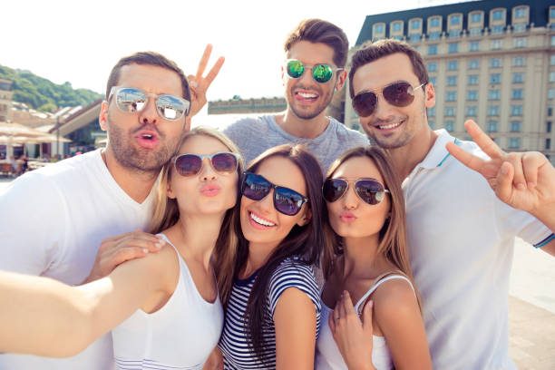 istock Young happy friends pouting and gesturing v-sign while making selfie 638717700