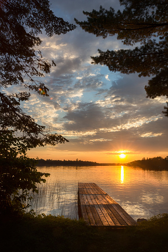 The sun rising over a small island far away on the seashore horizon.