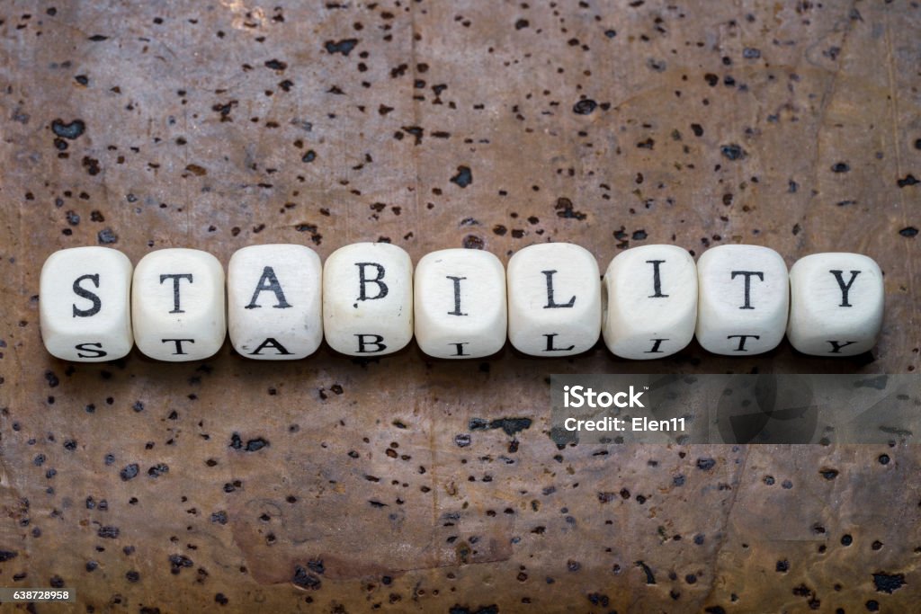 Stability text on wooden cubes Stability text on wooden cubes on a brown cork background Alphabet Stock Photo