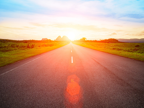 asphalt road with yellow blue sky background and Lens Flare or sunspot during sunset