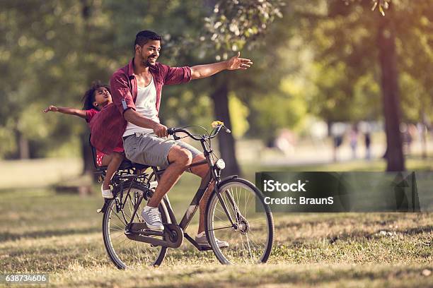 Carefree African American Father And Daughter Cycling In The Park Stock Photo - Download Image Now