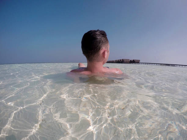 A young adult swimming in crystal clear water.