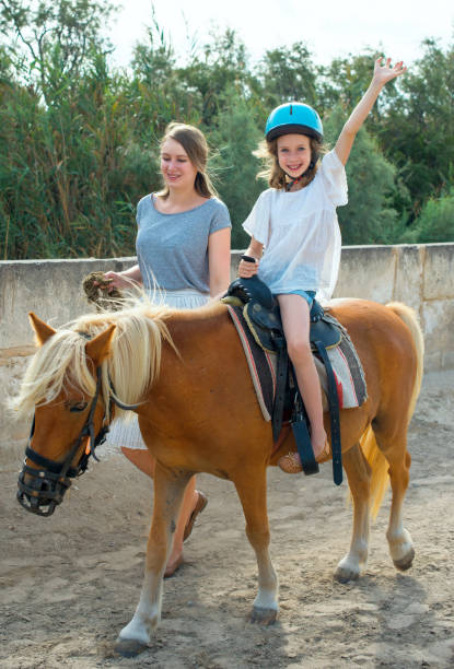 donna che guida pony con bambina. - teaching child horseback riding horse foto e immagini stock