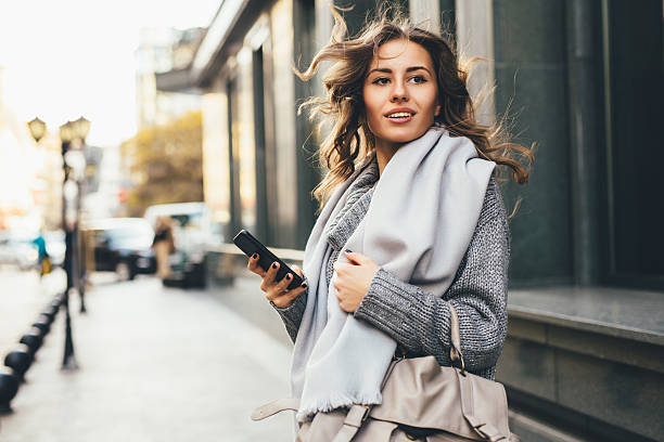 mujer enviando mensajes de texto al aire libre - wind scarf women people fotografías e imágenes de stock