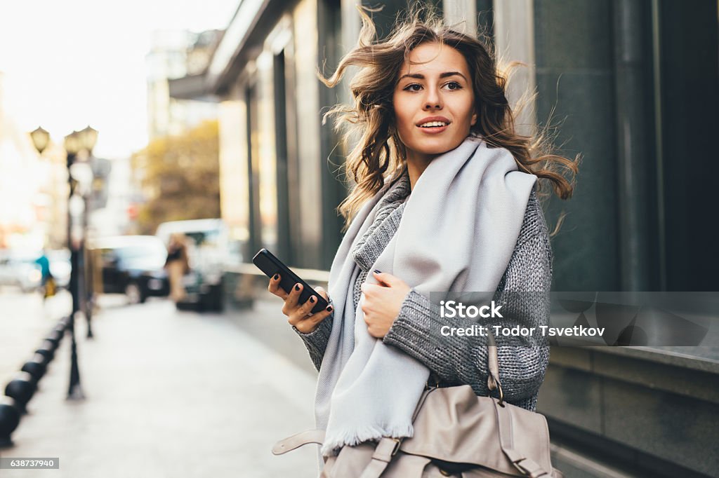 Woman texting outdoors A young woman texting on the phone outdoor in the city. Women Stock Photo