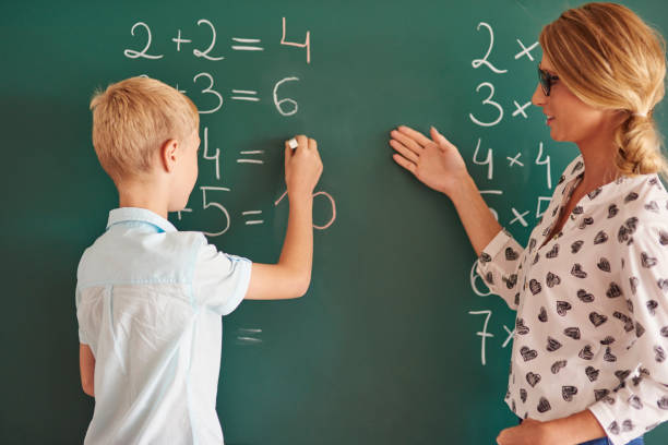istock Student boy with chalk next to the chalkboard 638742538