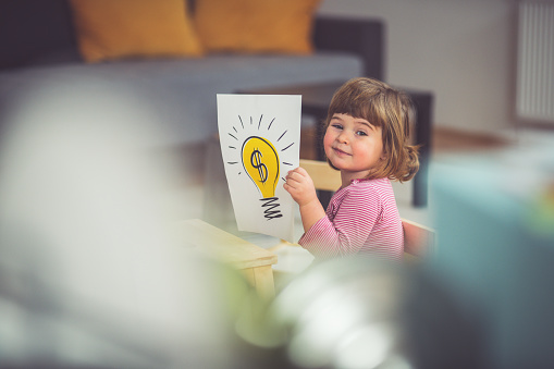 Baby girl holding paper with drawing of a dollar sign and lightbulb