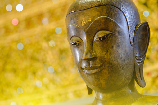 close up face on buddha head statue with Bokeh background and lighting effect.      Selective focus face buddha statue.
