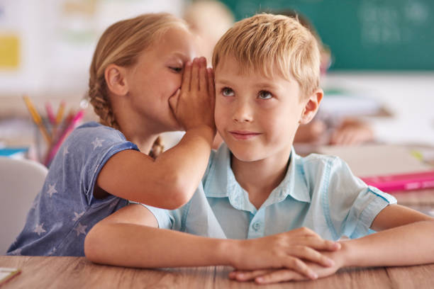 istock Boy and girl whispering in classroom 638747336
