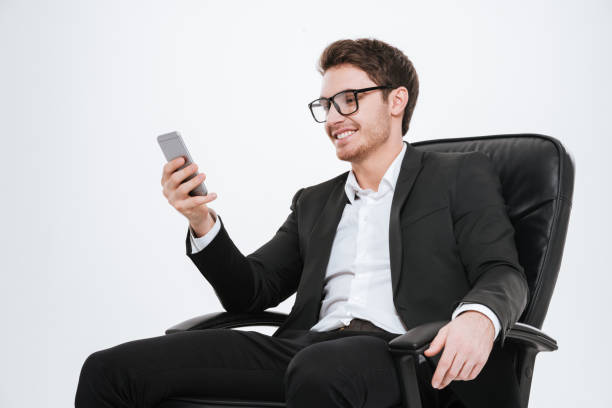 istock Smiling businessman using cell phone while sitting on a chair 638747930
