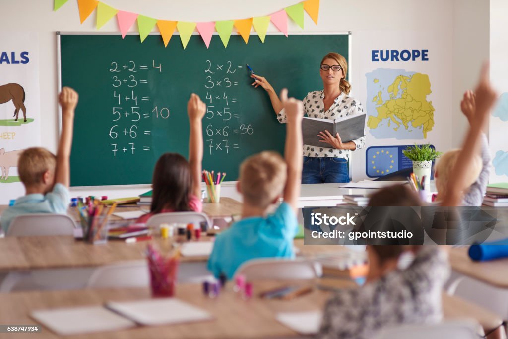 Many hands of volunteers during Maths class Classroom Stock Photo