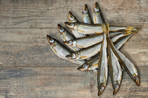 Salty stockfish on wooden table. Rainbow smelt (Osmerus mordax)