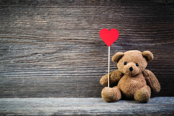 istock Teddy bear with heart sitting on old wood background. 638752032