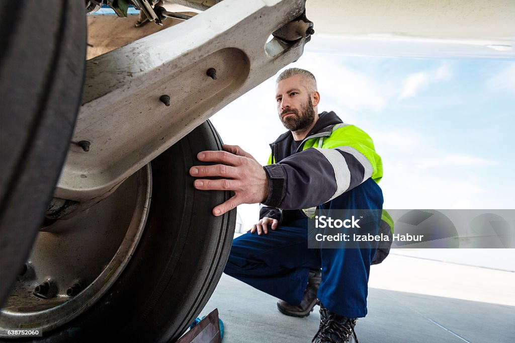Airport worker checking tires Airport worker chcecking aircraft chassis. Close up. Airplane Stock Photo