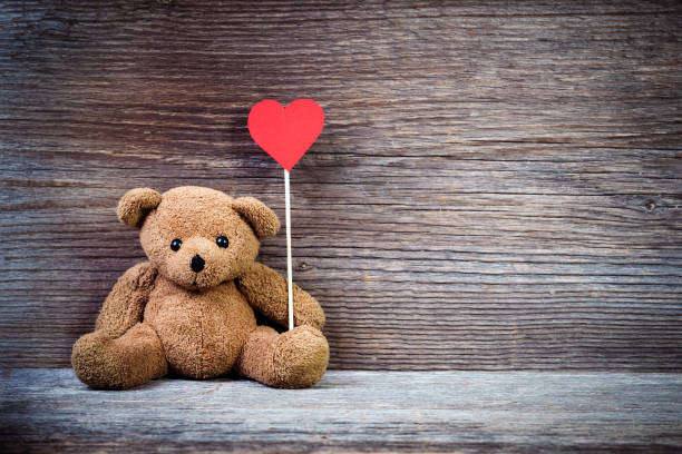 istock Teddy bear with heart sitting on old wood background. 638752108