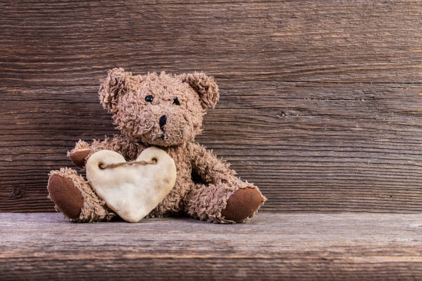 istock Teddy bear with heart sitting on old wood background. 638753324