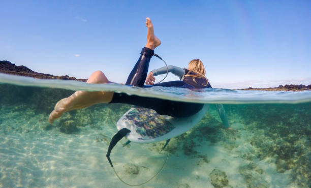 over unter foto von frauen paddeln auf einem surfbrett - fuerteventura stock-fotos und bilder