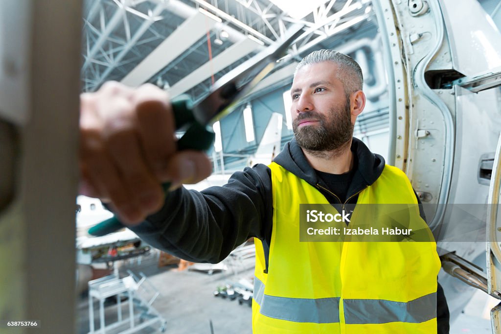 Aircraft engineer in a hangar Aircraft engineer standing in a hangar, looking away. Airplane Mechanic Stock Photo