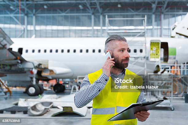 Aircraft Engineer Talking On Mobile Phone In A Hangar Stock Photo - Download Image Now