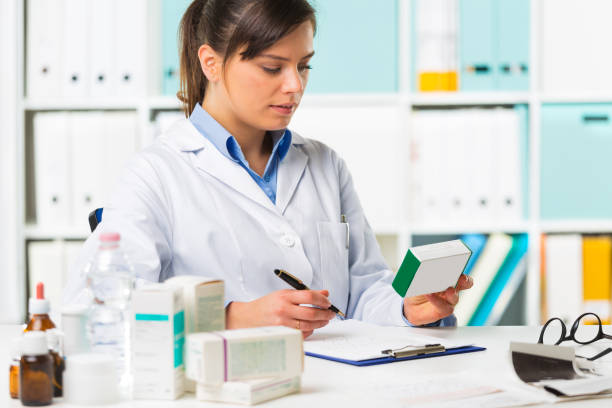 Female pharmacist sat at desk writing notes stock photo