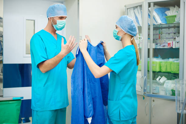krankenschwester hilft chirurg vor der operation - operationskittel stock-fotos und bilder