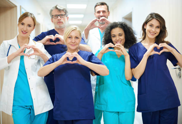 groupe de médecins avec symbole cardiaque - healthcare and medicine smiling group of people lab coat photos et images de collection