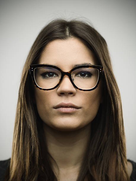 Close-up portrait of confident young woman Close-up portrait of confident young woman. Beautiful female is against gray background. She is with long brown hair and wearing glasses. Vertical studio photography from a DSLR camera. Sharp focus on eyes. mediterranean woman portrait stock pictures, royalty-free photos & images